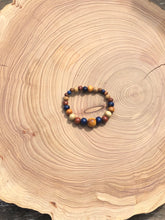 Load image into Gallery viewer, handmade beaded bracelet on elastic. Made out blue, brown and beige recycled beads.
