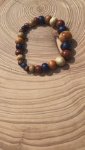 Load and play video in Gallery viewer, handmade beaded bracelet on elastic. Made out blue, brown and beige recycled beads.
